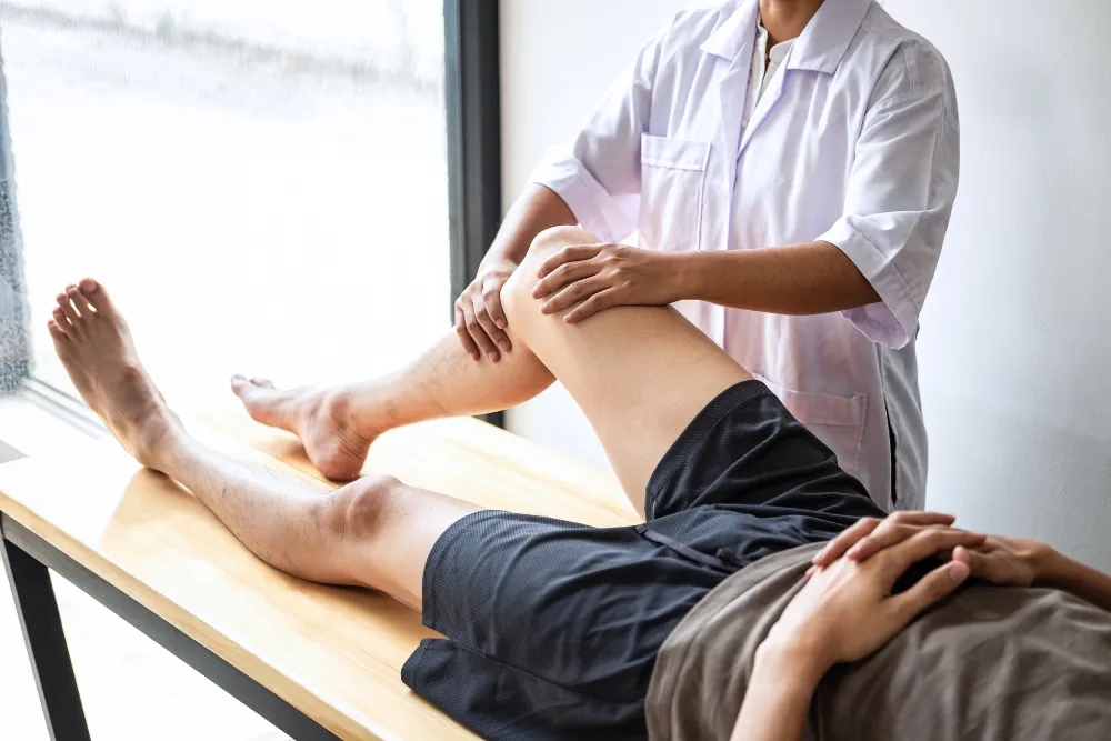 Physiotherapist examining a patient's knee during a clinic assessment