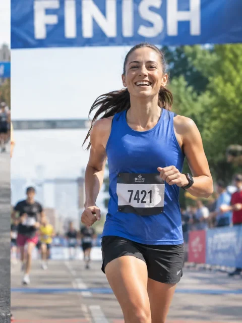 Same runner smiling as she crosses the finish line